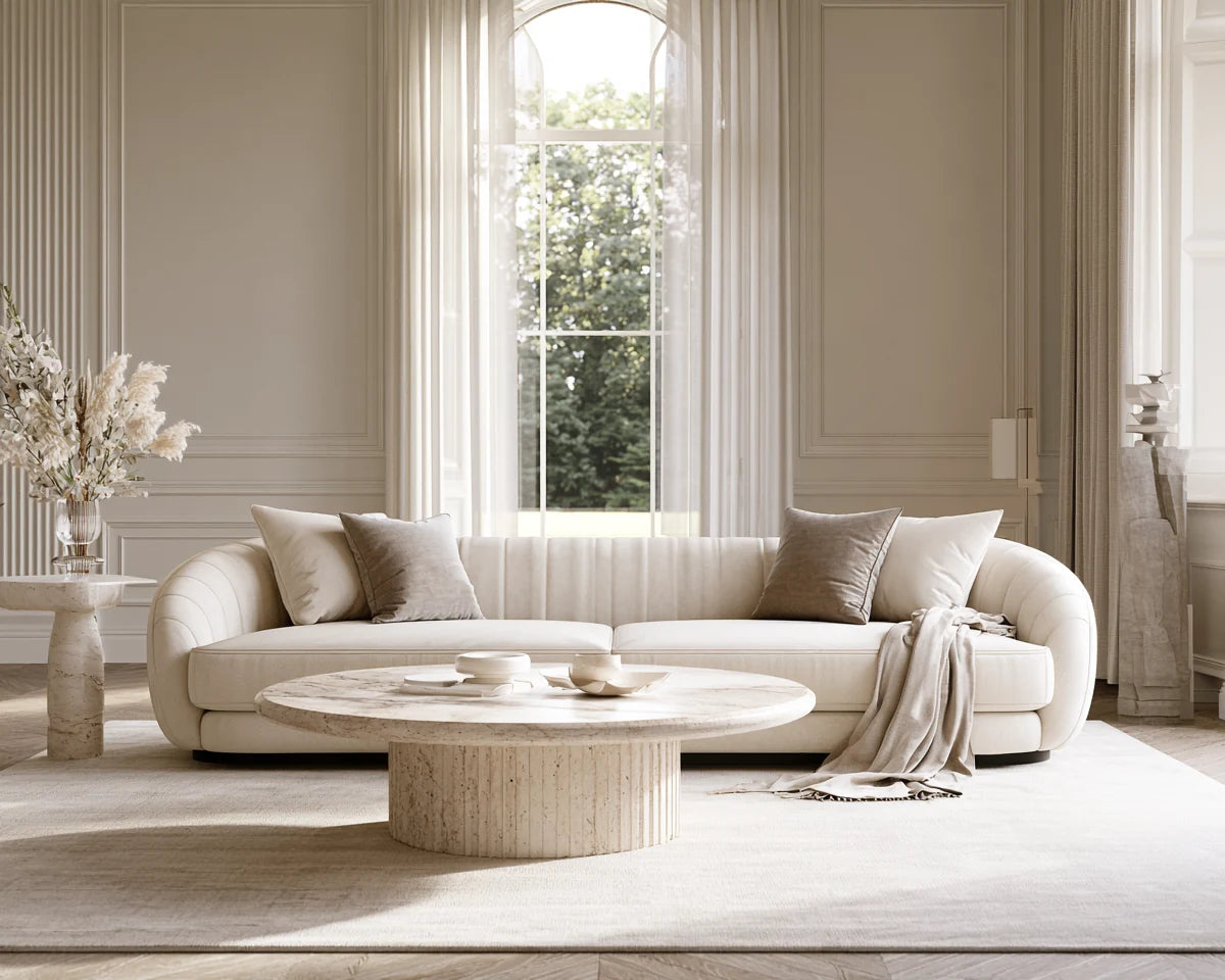 Elegant ivory three-seater sofa, neutral cushions and travertine table in a proportioned British living room